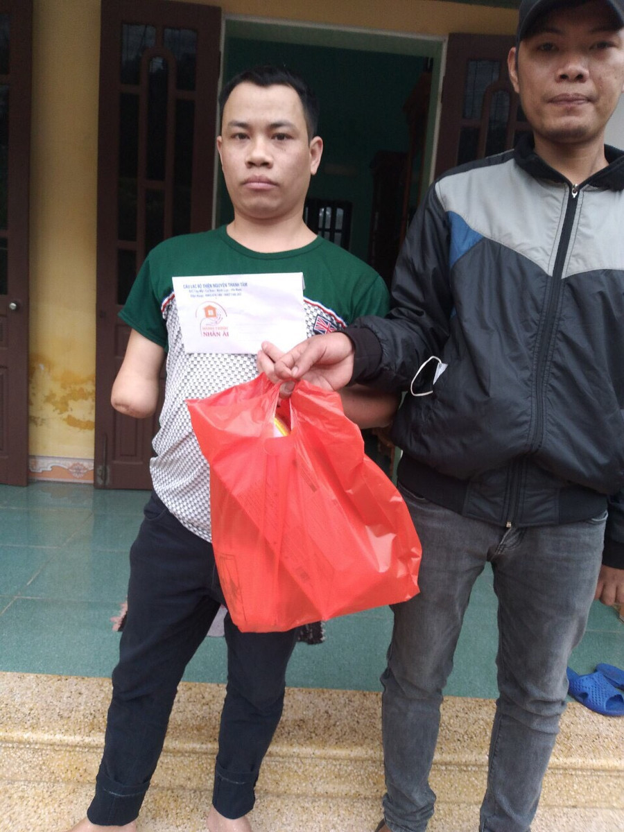 Anh Nguyễn Văn Cần (bên phải) tặng quà cho thanh niên khuyết tật có hoàn cảnh khó khăn.