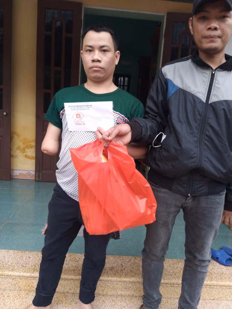 Anh Nguyễn Văn Cần (bên phải) tặng quà cho thanh niên khuyết tật có hoàn cảnh khó khăn.