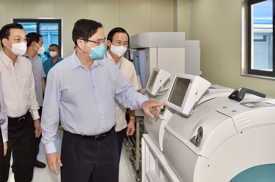 Thủ tướng Phạm Minh Chính kiểm tra hệ thống máy xét nghiệm Covid-19 tại phòng Lab của bệnh viện. Nguồn: BYT.