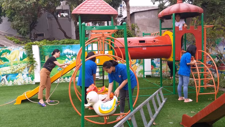 Giáo viên Trường Mầm non Hoa Phượng cùng các Đoàn viên thanh niên lau rửa đồ chơi ngoài trời bằng dung dịch khử khuẩn, đảm bảo an toàn phòng dịch Covid-19 khi trẻ đến trường.