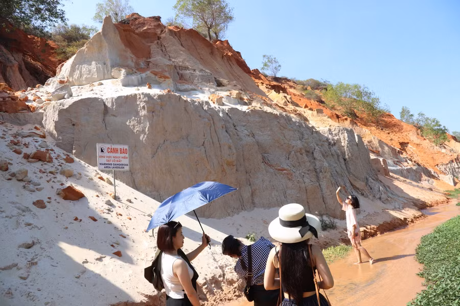 Bên cạnh suối có nhiều lối đi dẫn lên đồi cát. Du khách có thể men theo đó để ngắm nhìn toàn cảnh suối Hồng từ trên cao với những ngôi nhà thấp thoáng xen lẫn với hàng dừa xanh, những nhũ đá cát hoà quyện cùng dòng nước uốn quanh mềm mại lấp lánh dưới ánh nắng, thích hợp để du khách chụp một vài bức ảnh “sống ảo” làm kỷ niệm.