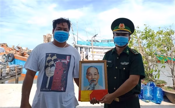 Ngư dân Ngô Văn Bông trú tại xã Bình Thắng phấn khởi khi được cán bộ Biên phòng tặng ảnh Bác Hồ và cờ Tổ quốc trước khi ra khơi.