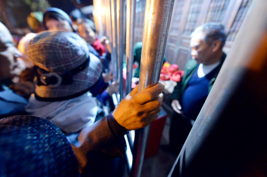 Người đàn ông bám tay vào song sắt ở đền Trùng Hoa để giữ chỗ, tránh bị xô đẩy dạt ra ngoài. Người đàn ông bám tay vào song sắt ở đền Trùng Hoa để giữ chỗ, tránh bị xô đẩy dạt ra ngoài.