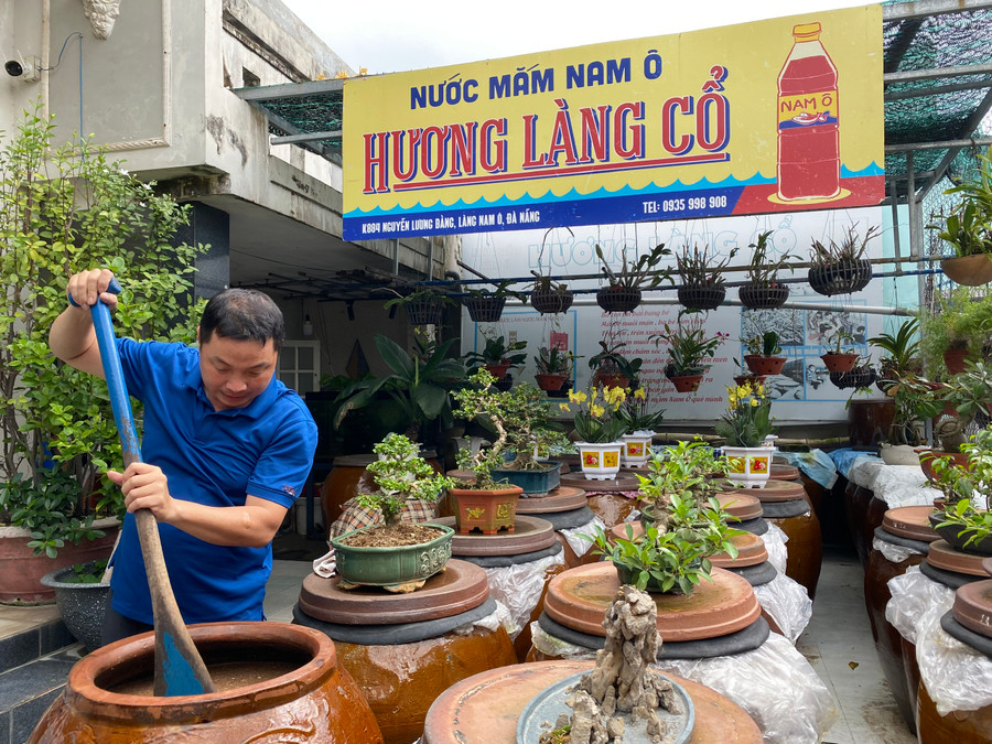 Anh Bùi Thanh Phú - giáo viên dạy Tin học Trường THPT Phạm Phú Thứ (TP Đà Nẵng), chủ xưởng sản xuất nước mắm Nam Ô Hương Làng Cổ, bên những chum nước mắm của gia đình.