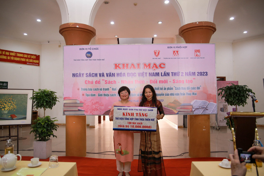 Bà Khúc Thị Hoa Phượng, Giám đốc - Tổng biên tập Nhà xuất bản Phụ nữ Việt Nam (bên trái) trao tặng 100 tên sách cho bà Hoàng Thị Kim Oanh – Giám đốc Thư viện Tổng hợp tỉnh Thừa Thiên - Huế (bên phải) tại lễ khai mạc.