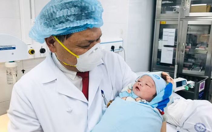 Giám đốc Bệnh viện Phụ sản TƯ Trần Danh Cường bế bé Nguyễn Nhật Anh Khôi. em bé đầu tiên chào đời tại bệnh viện năm 2022. Ảnh: HNM.