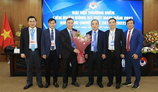 Quyền chủ tịch Liên đoàn Bóng đá Việt Nam Trần Quốc Tuấn nhận hoa chúc mừng từ Nguyên Chủ tịch Liên đoàn Bóng đá Việt Nam khóa VIII Lê Khánh Hải. Ảnh: TTXVN.