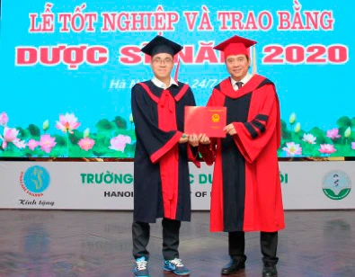 Thủ khoa Ngô Minh Khoa (bên trái) đón nhận bằng tốt nghiệp xuất sắc.