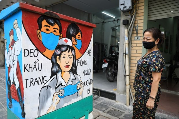 Người dân xem những bức tranh cổ động về công tác phòng chống dịch Covid-19. Ảnh: TTXVN.
