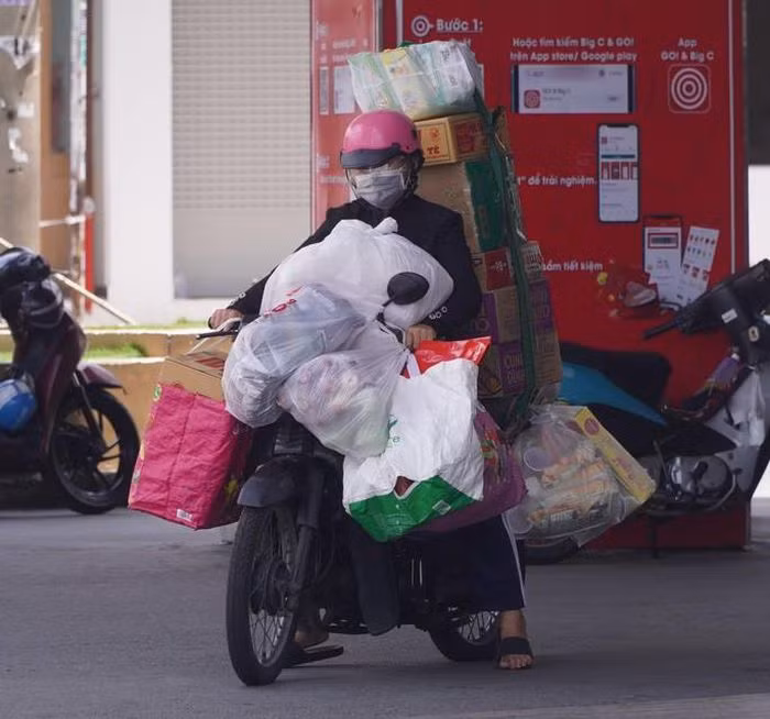 Một người phụ nữ mua thực phẩm quá nhiều khiến việc điều khiển xe khó khăn. Nguồn: NLĐ.