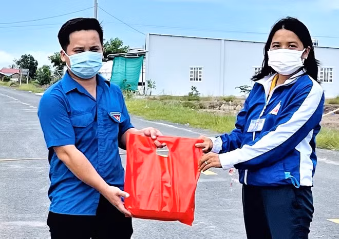 Anh Lâm Chí Cương (trái, 27 tuổi, Bí thư đoàn ấp Sông Cái 1, xã Tham Đôn, tỉnh Sóc Trăng) đã giúp đỡ 1 sản phụ sinh con tại chốt kiểm soát Covid-19. Trong ảnh: Anh Cương được lãnh đạo Đoàn cấp trên tặng quà chiều 10/8. Ảnh: Nhật Tân.