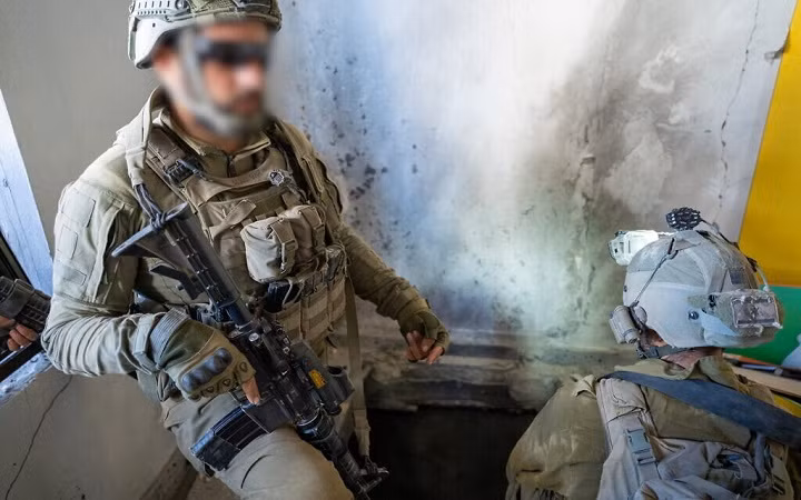 Một sĩ quan kỹ thuật chiến đấu chỉ một đường hầm mà họ tìm thấy bên trong một ngôi nhà ở phía bắc Gaza, ngày 7/11/2023