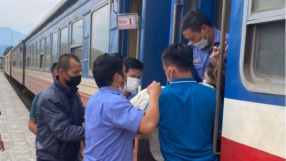 Nhân viên đường sắt hỗ trợ đưa mẹ con sản phụ xuống tàu tại ga Đồng Lê. Ảnh: SGGP.