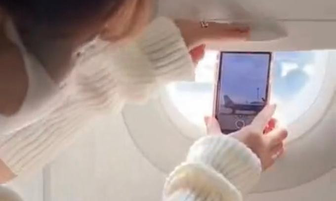 Hành động dùng tấm chắn trên cửa sổ máy bay để giữ điện thoại xuất hiện trên video của một TikToker nổi tiếng ở Việt Nam. Ảnh chụp màn hình.