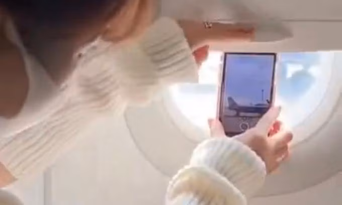 Hành động dùng tấm chắn trên cửa sổ máy bay để giữ điện thoại xuất hiện trên video của một TikToker nổi tiếng ở Việt Nam. Ảnh chụp màn hình.