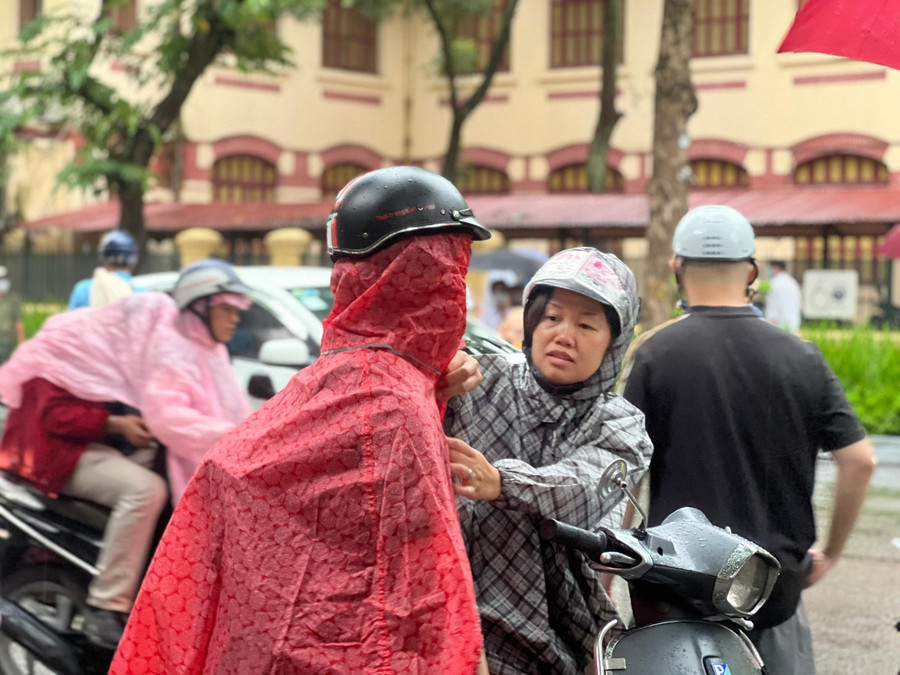 Phụ huynh chỉnh áo mưa cho con trai vừa ra khỏi phòng thi. Phụ huynh chỉnh áo mưa cho con trai vừa ra khỏi phòng thi.