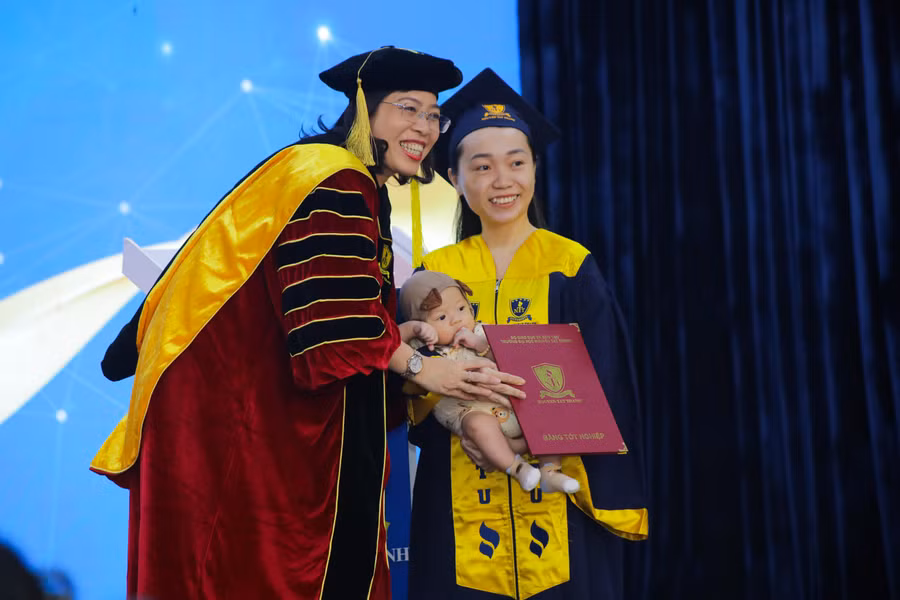 Hình ảnh hết sức dễ thương khi em bé theo mẹ lên nhận bằng tốt nghiệp.