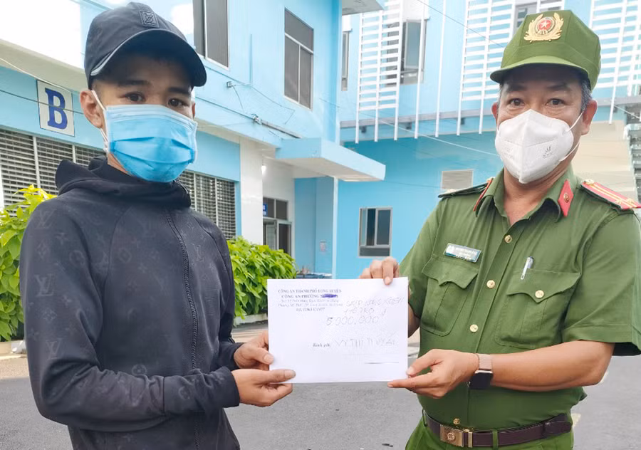 Trung tá Huỳnh Thanh Đảo, Trưởng Công an phường Mỹ Thạnh đại diện Công an thành phố Long Xuyên trao hỗ trợ 5 triệu đồng cho vợ chồng anh Vĩ, chị Ái. Ảnh: Minh Anh.
