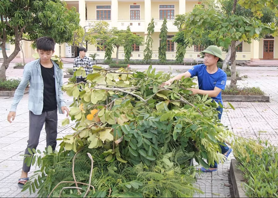 Thầy Quyết (bên phải) cùng học trò dọn vệ sinh sân trường.