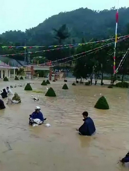 Giáo viên đội mưa để chuyển tài sản, xe máy ra khỏi vùng nước ngập