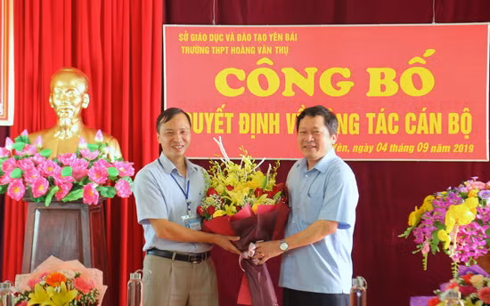 Ông Vương Văn Bằng - Giám đốc Sở GD&ĐT (bên phải) trao quyết định và tặng hoa chúc mừng Hiệu trưởng Phạm Văn Thư.