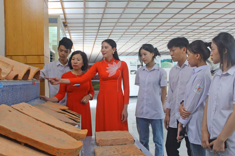 Cô Lan Anh (thứ 2 từ trái qua) cùng học trò nghe hướng dẫn viên giới thiệu về hiện vật được trưng bày tại Thành Nhà Hồ.