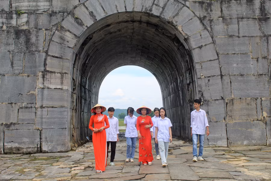 Cô và trò Trường THPT Vĩnh Lộc được hướng dẫn viên du lịch (bìa trái) giới thiệu về di sản Thành Nhà Hồ.