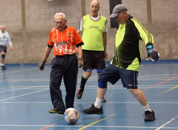 Cụ Fisher (áo đỏ) vẫn thường xuyên thi đấu bóng đá với những người bạn già.