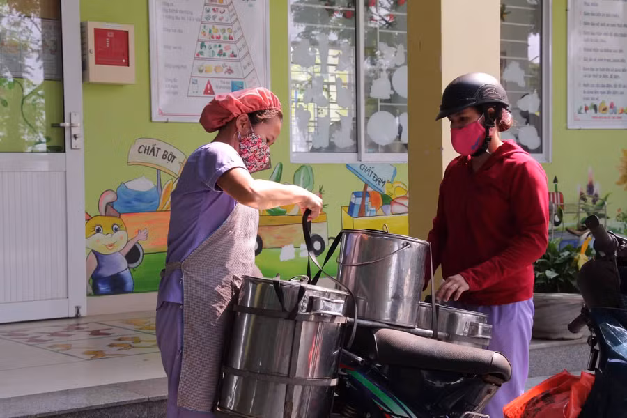 Các cô cấp dưỡng của Trường Mầm non Hòa Phong chuyển thức ăn đến điểm trường lẻ. Ảnh: T.G
