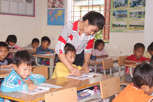 Cô giáo hướng dẫn học sinh học bài trên lớp