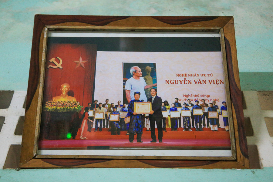 Hàng loạt sản phẩm cùng các Bằng khen, Giấy khen, Giấy chứng nhận được trưng bày tại một góc nhà (ảnh trái) và hình ảnh ông Viện nhận danh hiệu Nghệ nhân Ưu tú được Chủ tịch nước phong tặng (ảnh phải). (Ảnh: Hoàng Hải)