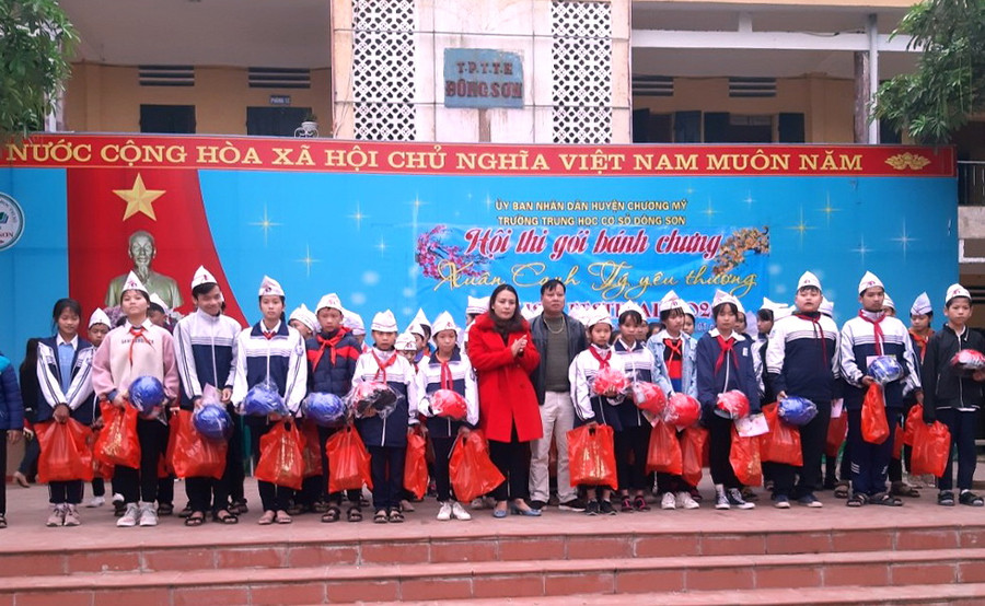 Nhà giáo Tô Thị Bích Liên (mặc áo choàng đỏ) trao tặng các phần quà cho học sinh trước thềm Tết Nguyên đán.