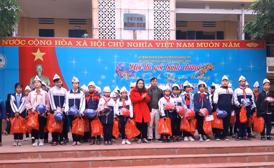 Nhà giáo Tô Thị Bích Liên (mặc áo choàng đỏ) trao tặng các phần quà cho học sinh trước thềm Tết Nguyên đán.
