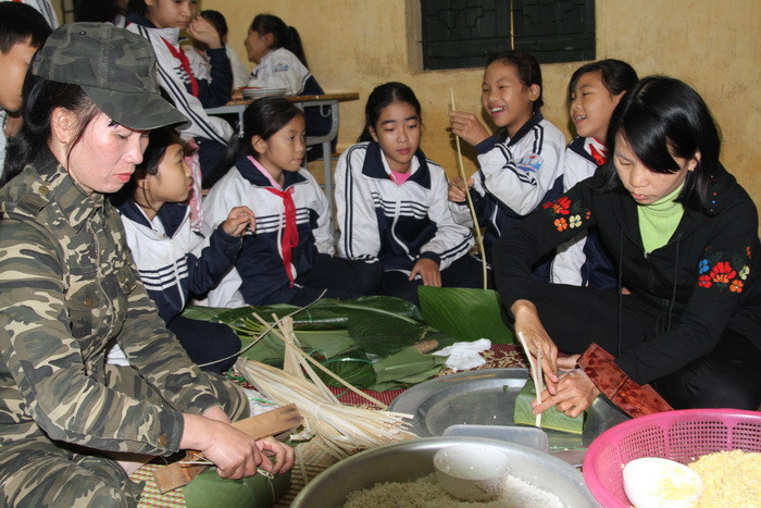 Các bạn nữ háo hứng theo dõi các bà, các mẹ để học cách gói bánh chưng.