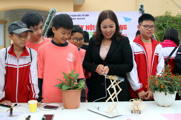 Nhà giáo Hoàng Ngọc Lan trải nghiệm mô hình cần trục nâng thủy lực được học sinh lớp 7 chế tạo từ những vật liệu dễ kiếm.