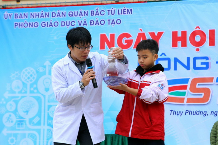 Học sinh giao lưu với thầy Đỗ Minh Đức - Một Đại sứ STEM từ Học viện Sáng tạo S3 với thí nghiệm "Lắc chai đổi màu": Sử dụng dung dịch gồm có kiềm (NaOH) trộn với nước đường Glucozơ; Hỗn hợp dung dịch này đổi màu khi lắc với chất chỉ thị xanh - Metylen. Ảnh: Việt Hà