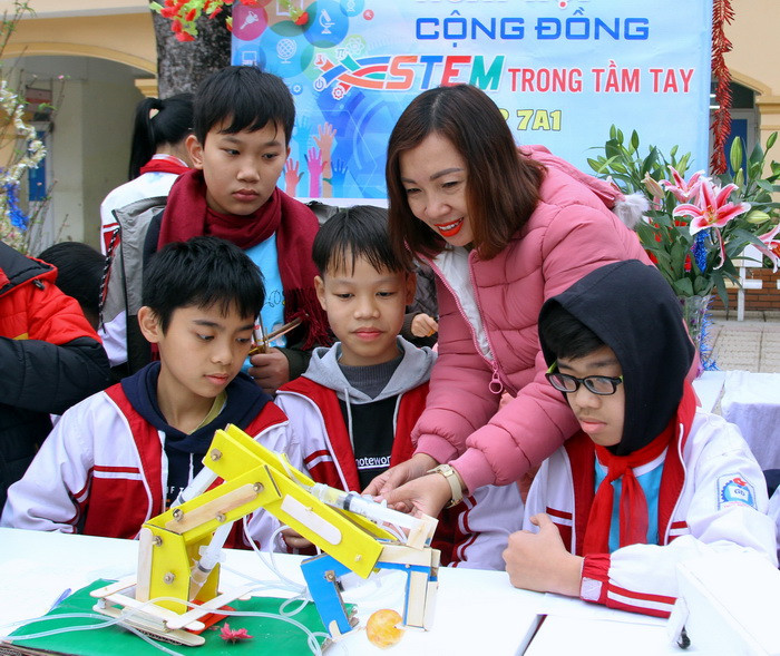 Cô Nguyễn Thị Diệu - Giáo viên Trường THCS Thụy Phương với học sinh lớp 7A1 trải nghiệm sản phẩm tự làm: Cánh tay máy xúc. Ảnh: Việt Hà