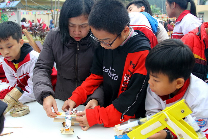 Những học sinh này đang rất thích thú khi được giáo viên hướng dẫn làm mô hình máy bay chiến đấu cánh quạt. Ảnh: Việt Hà