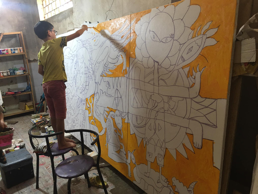 Hoàng Nhật Quang đang vẽ một bức tranh khổ lớn.