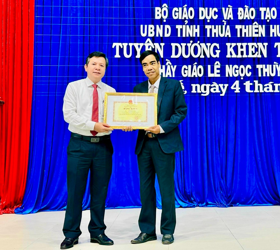 Ông Nguyễn Tân (bên trái) - Giám đốc Sở GD&ĐT tỉnh Thừa Thiên - Huế thừa ủy quyền trao Bằng khen của Bộ GD&ĐT và UBND tỉnh cho thầy giáo Lê Ngọc Thùy.