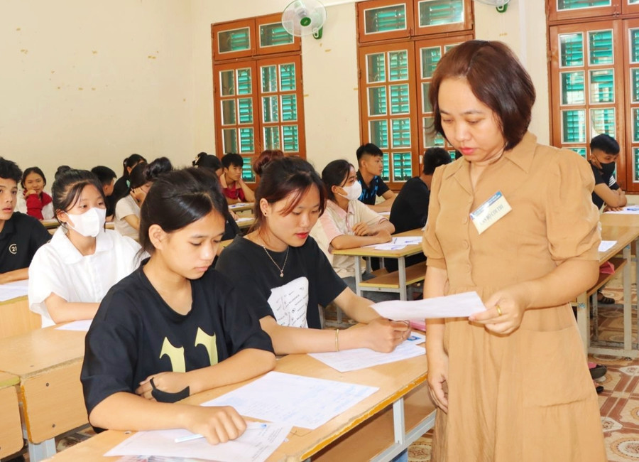 Cán bộ coi thi kiểm tra thủ tục dự thi của học sinh.