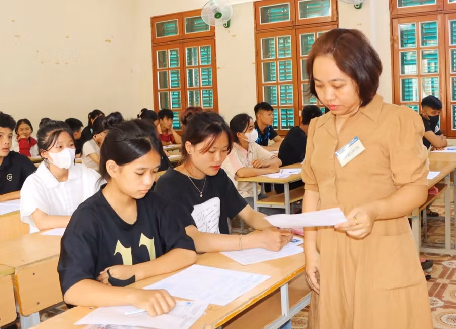 Cán bộ coi thi kiểm tra thủ tục dự thi của học sinh.