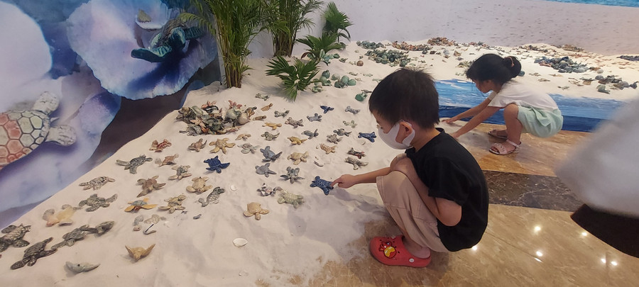 Các bạn nhỏ thích thú với &apos;bãi biển&apos; cát trắng được sắp đặt cùng rùa biển làm bằng gốm. Ảnh: Bình Thanh.