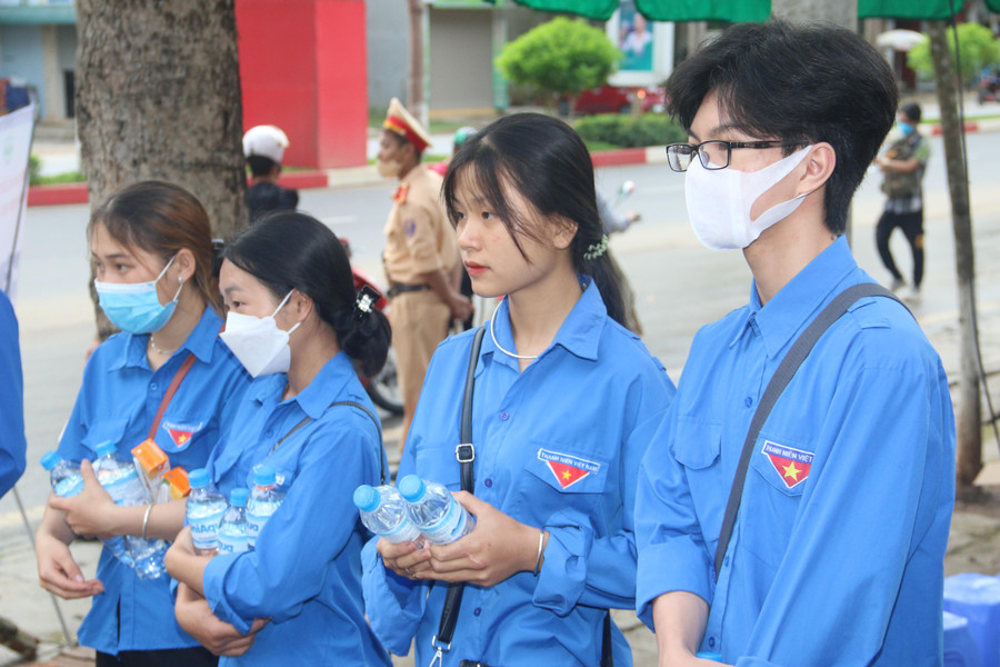 Các đoàn viên, thanh niên tình nguyện cầm trên tay nước lọc hỗ trợ thí sinh trước cổng trường.