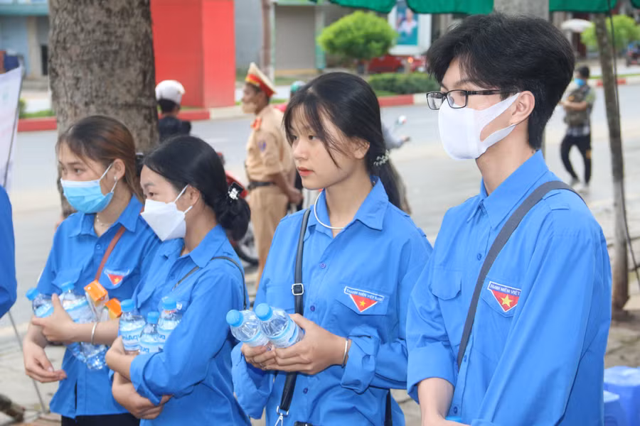 Các đoàn viên, thanh niên tình nguyện cầm trên tay nước lọc hỗ trợ thí sinh trước cổng trường.