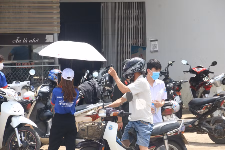 Phụ huynh học sinh đứng ngoài cổng trường chờ các sỹ tử thi môn thi tổ hợp.