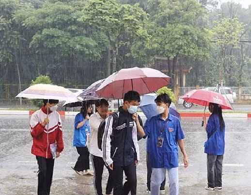 Mưa như trút các thí sinh ở Sơn La được bố mẹ che ô đưa đến điểm trường thi tốt nghiệp.