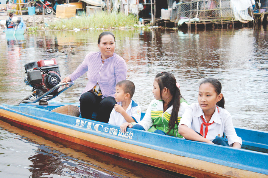 Phụ huynh ở huyện Trần Văn Thời (Cà Mau) chở con đến trường bằng xuồng máy. Ảnh: Q. Ngữ 