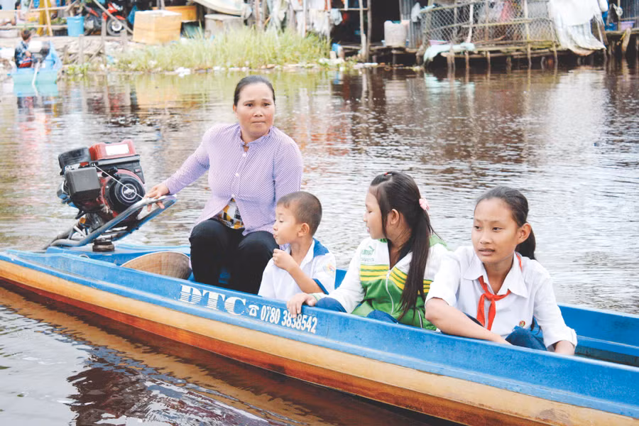 Phụ huynh ở huyện Trần Văn Thời (Cà Mau) chở con đến trường bằng xuồng máy. Ảnh: Q. Ngữ 