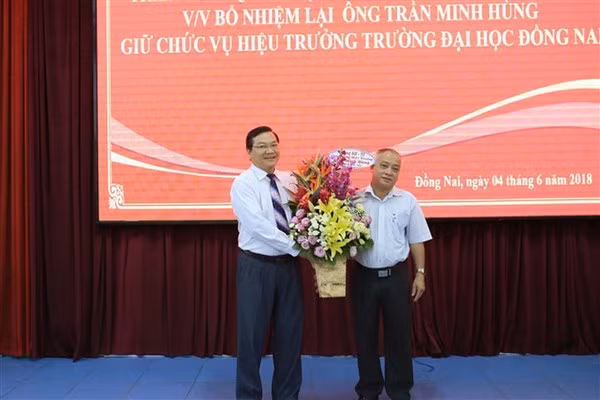 Ông Trần Minh Hùng (trái) nhận hoa chúc mừng khi được tái bổ nhiệm Hiệu trưởng Trường ĐH Đồng Nai (2018) và ông Phan Văn Thanh (cựu Trưởng phòng KHTC trường, vừa bị kỷ luật bằng hình thức khai trừ Đảng).